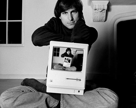 Steve jobs holding an apple machine